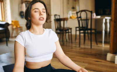 A woman practicing mindful breathing during morning meditation in a cozy indoor space, symbolizing the essence of mind-body healing — The Power Within.