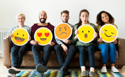 Five individuals holding posters of different emotions—happy, surprised, sad—reflecting emotional awareness as a path to spiritual growth.