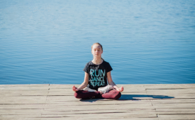 Girl meditating by the lake for inner healing and mind-body balance.