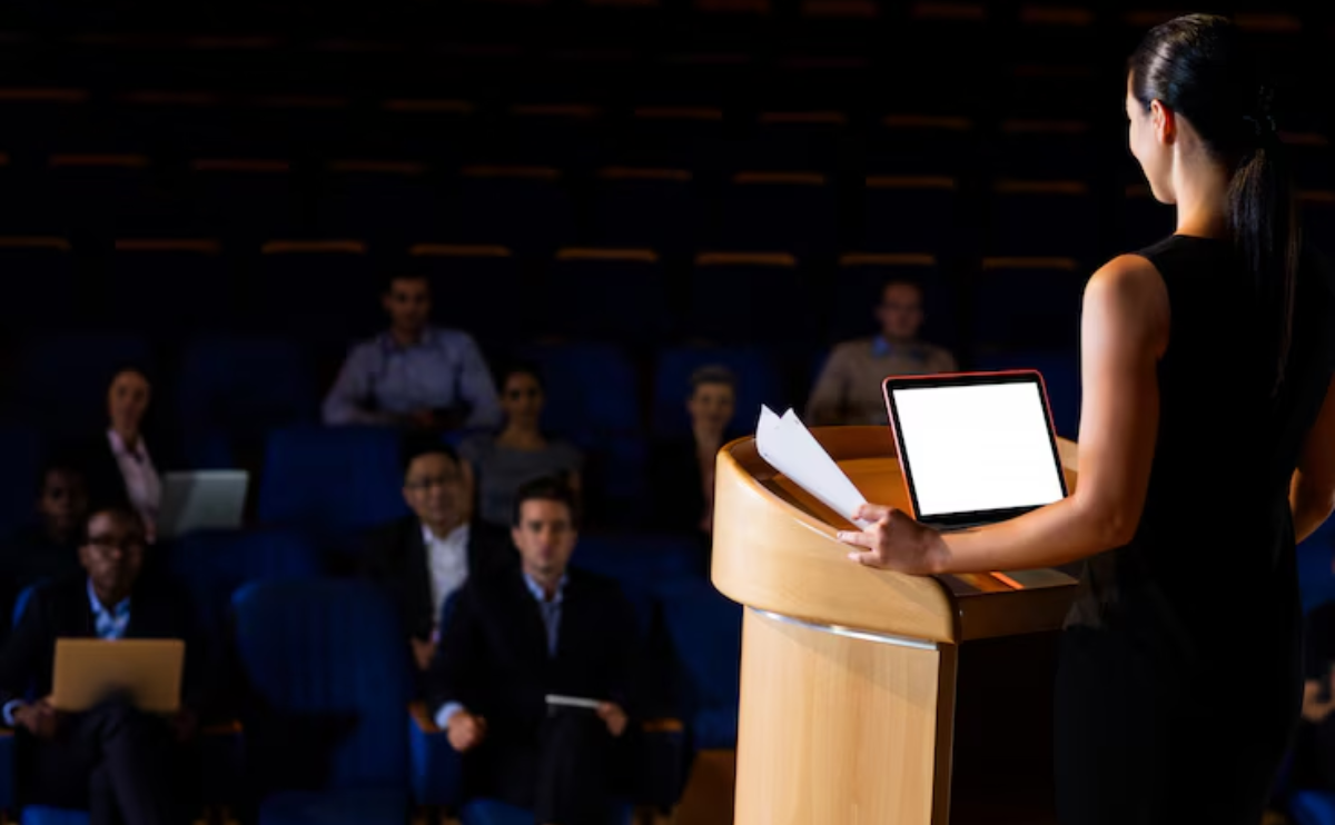 Confident woman delivering a speech on personal development in front of an audience.